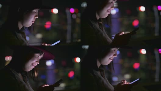 年轻的亚洲女人在新加坡城市的晚上用手机发短信高清在线视频素材下载