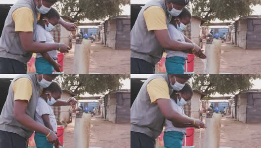 非洲黑人母亲在非正式定居点向孩子示范如何洗手预防Covid-19高清在线视频素材下载
