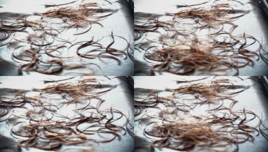 当发型师剪她的客户的头发时，头发掉落到地板上的极端特写高清在线视频素材下载