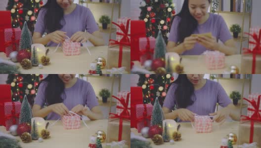 亚洲妇女打开礼盒与笑脸在家里的背景与圣诞树装饰节日节日。圣诞节庆祝活动的概念。4 k慢动作。高清在线视频素材下载
