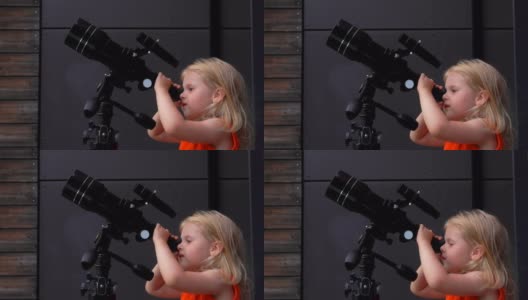 一个穿橙色上衣的小女孩正在通过望远镜探索天空高清在线视频素材下载