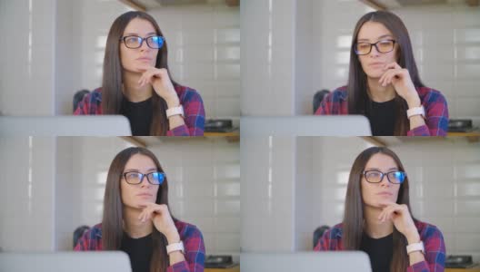 戴着眼镜的美丽白人女性在禁闭期间在家用笔记本电脑工作，思考着问题的解决方案。一个漂亮年轻女性在笔记本电脑前思考的4k视频高清在线视频素材下载