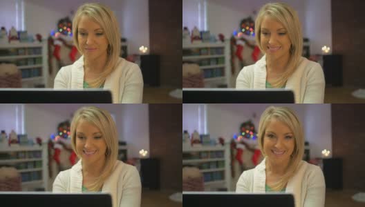 漂亮的金发女人在电脑上打字，看着镜头微笑高清在线视频素材下载