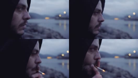 一个疯狂的男人坐在湖岸沉思和吸烟的特写镜头高清在线视频素材下载