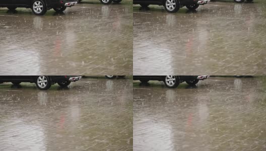 汽车在城市的停车场被淋湿了，有大雨，倾盆大雨，整个停车场都被水淹没了，大滴大滴的水滴溅进水坑里高清在线视频素材下载