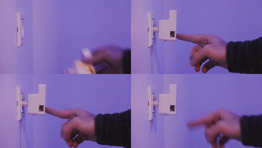 男子将WiFi中继器插入墙上的电源插座，然后用手指按WPS按钮高清在线视频素材下载