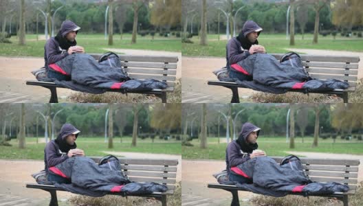 一个无家可归的人在公园的长椅上吃零食高清在线视频素材下载