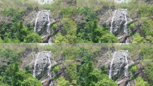 鸟瞰图的水从岩石悬崖从顶部向下到底部的绿色森林，4k高清在线视频素材下载