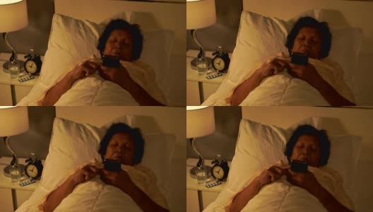 一个老女人晚上在床上玩手机高清在线视频素材下载