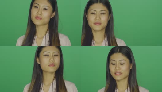 美丽的亚洲女人微笑，是诱人的，在一个绿色屏幕的工作室背景高清在线视频素材下载
