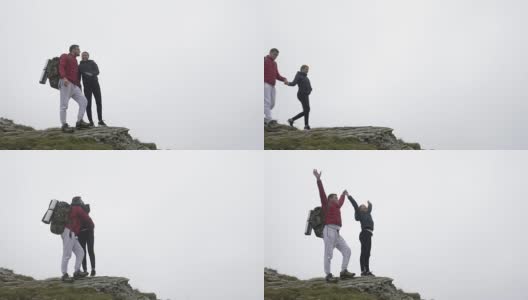 一对兴高采烈的青少年夫妇举起双手庆祝到达山顶，享受冒险高清在线视频素材下载