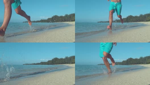 慢镜头:一个活跃的年轻人在潮湿的沙滩上慢跑。高清在线视频素材下载