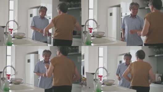 亚洲华人老年夫妇喜欢在厨房跳舞，同时在周末在家做饭高清在线视频素材下载