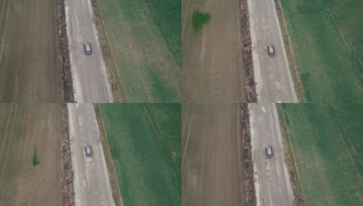 这辆车正行驶在穿过田野的道路上，无人机拍摄了航拍画面。秋天的时候在柏油路上，摄影机跟在车的后面。高清在线视频素材下载
