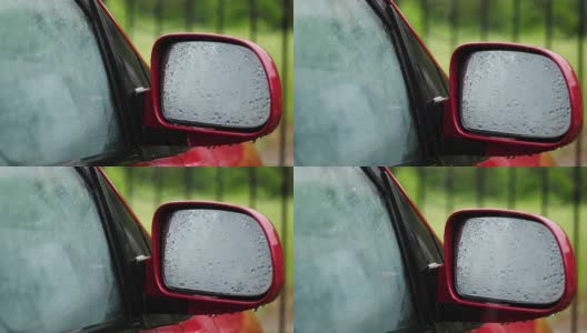 特写镜头，雨点在汽车的玻璃窗上滴落下来。雨点落在侧面的镜子上。有大雨，阵雨。雨滴落在汽车玻璃上高清在线视频素材下载