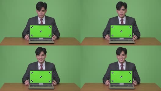 年轻英俊的亚洲商人在绿色背景下展示笔记本电脑高清在线视频素材下载