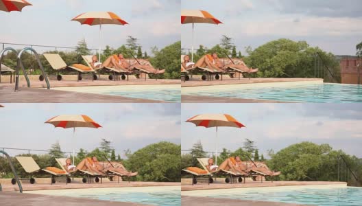 男人和女人躺在沙滩椅上，在游泳池旁晒日光浴高清在线视频素材下载