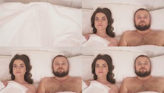 床上的白毯子的俯视图被拿走了，一个漂亮的黑发女人和一个留着胡子的男人躺在床上，瞪着他们高清在线视频素材下载