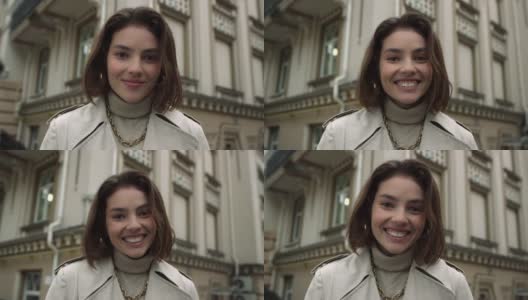 一个微笑的女人在老城区看着镜头。快乐的女孩在街上笑。高清在线视频素材下载