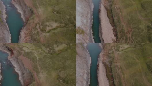 在冰岛，在悬崖和玄武岩墙之间的河流风景如画的航拍高清在线视频素材下载
