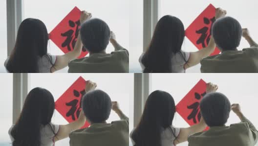 中国新年老人和她的女儿装饰房子的客厅与中国文字书法装饰的窗户准备家庭团聚高清在线视频素材下载