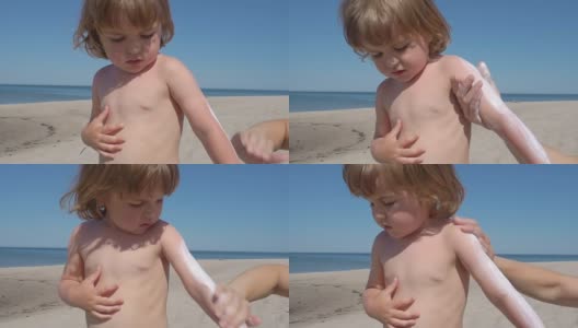 妈妈在海滩上给儿子涂防晒霜。母亲为孩子准备在海里洗澡。高清在线视频素材下载