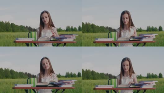 户外学校教育。选择教育。一个学龄女孩坐在书桌前，周围是大自然高清在线视频素材下载