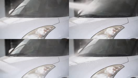 水雾正在清洗一辆白色汽车。在车库封闭水喷清洗车辆前车裙部。工人使用水喷淋车辆。高清在线视频素材下载