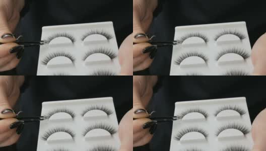化妆师与专业化妆师用特制镊子将黑色长而蓬松的假睫毛装在特制的盒子里。高清在线视频素材下载