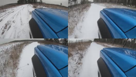 蓝色的汽车在雪地上行驶。从引擎盖上看。穿越森林道路的时间间隔。高清在线视频素材下载