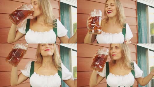 一个女人急切地从一个大玻璃杯里喝啤酒。在十月音乐节上，德国民族传统。情绪化的面部表情，红色的口红高清在线视频素材下载