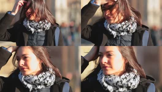 在寒冷的冬天，一名女子一边整理头发，一边在城市街道上以4K / 60fps的慢镜头行走。日落时分，一个女人走在人行道上高清在线视频素材下载