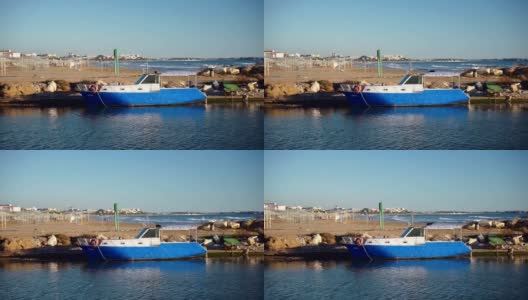 沿着海滩上有木甲板系泊的旧船移动高清在线视频素材下载