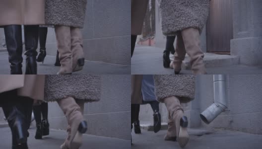 镜头跟随穿着秋日高跟靴在街上行走的女性脚步。三个时髦的女人来到大楼入口处。生活方式,时尚。缓慢的运动。高清在线视频素材下载