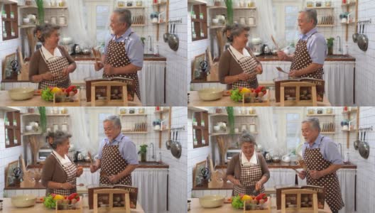 资深亚洲情侣在厨房里一起快乐做饭，退休后幸福生活。高清在线视频素材下载