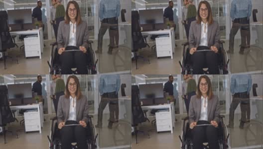 残疾人商务妇女在办公室里坐着轮椅，扶着桌子微笑高清在线视频素材下载