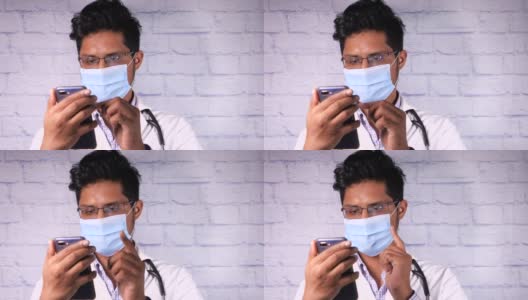 医生戴着防护口罩在医院使用智能手机。高清在线视频素材下载