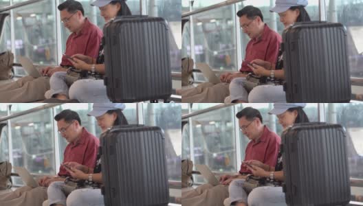 幸福的亚洲老年夫妇坐在地板上使用笔记本电脑和智能手机在候机楼机场等待离开。老年人的旅程。老夫老妻。旅行。飞行。退休高清在线视频素材下载