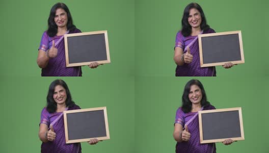 成熟快乐美丽的印度女人微笑着展示黑板，竖起大拇指高清在线视频素材下载