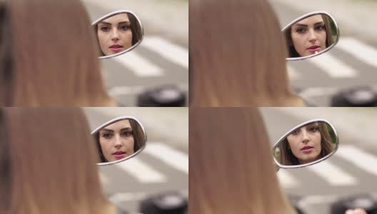 女孩对着摩托车的镜子画嘴唇。高清在线视频素材下载