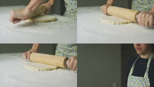 倾斜下来的镜头，一个白人妇女在她的30多岁用一个木制擀面杖擀出一个圆形的面团平在一个轻面粉白色的桌子上高清在线视频素材下载