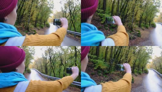 女游客用手机拍照用于社交媒体，森林路高清在线视频素材下载