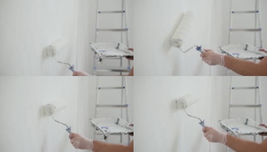 英俊成熟的男人在公寓里修理。那个人用滚筒把墙刷成白色。做你自己。DIY。高清在线视频素材下载
