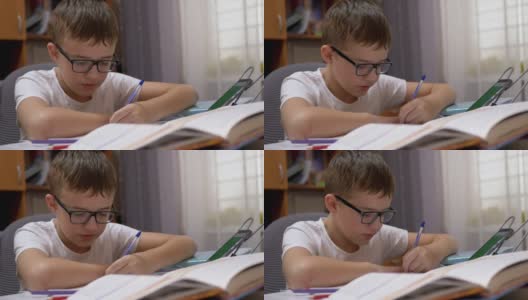 戴眼镜微笑的小男生用笔记本用笔写字，用智能手机说话高清在线视频素材下载