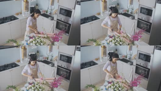 亚洲华人女性花商，小企业主，在厨房为花束剪包装纸，在家里工作，日常运作一个小生意高清在线视频素材下载