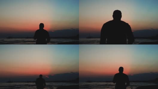 史诗般的电影剪影，快乐的游客与相机享受惊人的红色日落在海边，向前走。高清在线视频素材下载