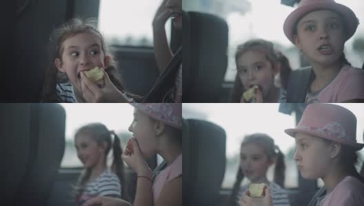 两姐妹坐上一辆旅游巴士，望着窗外，吃着苹果。高清在线视频素材下载