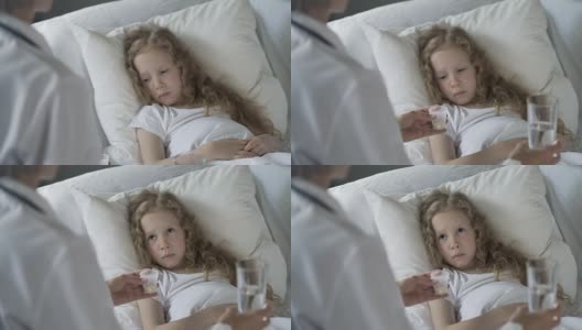 护士给免疫系统低下、流感流行的不开心孩子吃药高清在线视频素材下载