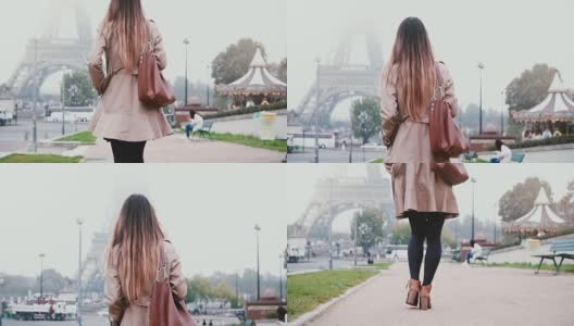 后视图的年轻女子穿着法国风格步行到埃菲尔铁塔在巴黎，法国。女孩看着著名的风景高清在线视频素材下载