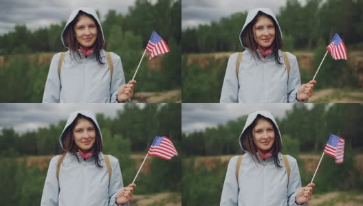慢动作的肖像，骄傲的美国公民挥舞着美国国旗与高兴的微笑，看着相机。民族自豪感、美丽自然、健康生活理念。高清在线视频素材下载